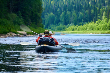 couple in a two-seater kayak rafting down the river among the mountains