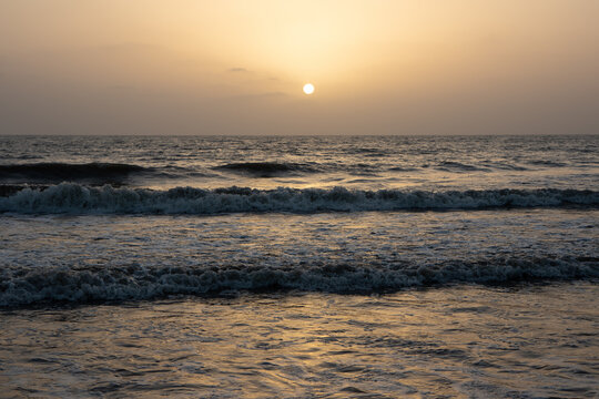 A view of sun setting in the horizon and waves in the ocean