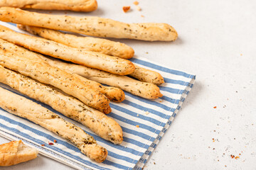 Homemade breadsticks with herbs on a gray concrete background. Grissini - Italian breadsticks
