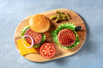 Burgers on a wooden board. Homemade hamburger recipe. Barbecue grilled beef patties with green...