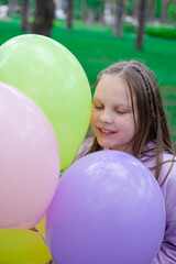 pretty teenage girl with colorful balloons in purple costume in park. happy kids. summer days. vacation, holidays