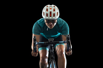 Professional young female cycler on road bike isolated over black studio background.