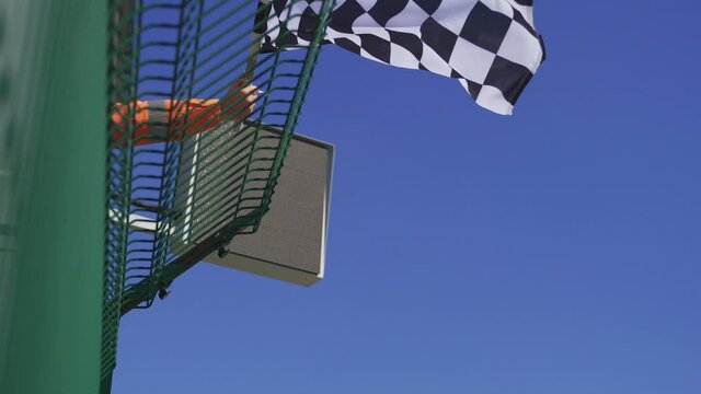 Man holding and waving Checkered race at finish line on a raceway. Victory, achievement, success and sport concept. 