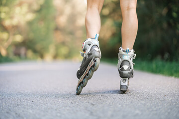 Roller skater close up in action from behind on asphalt road in woods outdoors. Roller skates shoe.