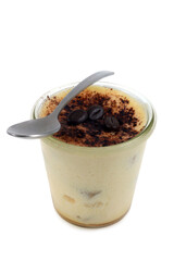 Tiramisu maison au café servi dans un ramequin avec une cuillère sur fond blanc