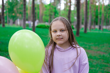 pretty teenage girl with colorful balloons in purple costume in park. happy kids. summer days. vacation, holidays