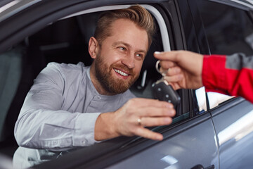 Mechanic giving car keys to happy customer in repair service salon