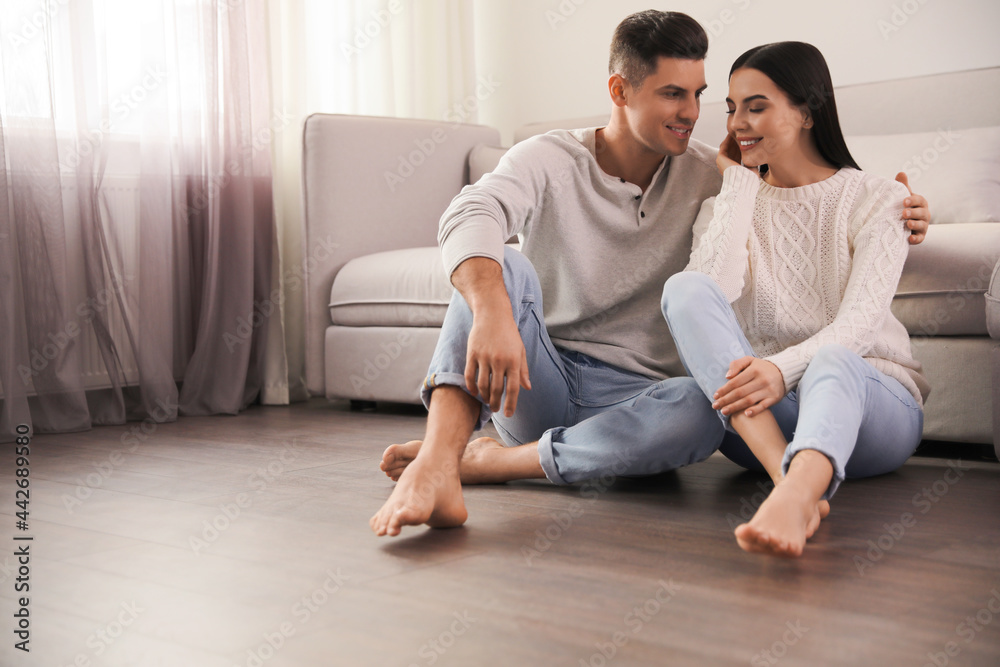 Canvas Prints Happy couple sitting on warm floor in living room, space for text. Heating system