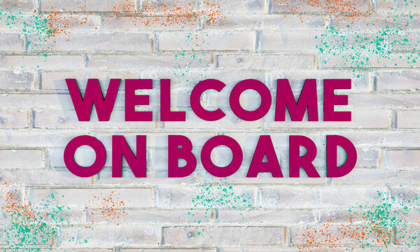 Welcome on board. 3D letters in dark purple on a bright brick wall, with some colored paint-splatter.