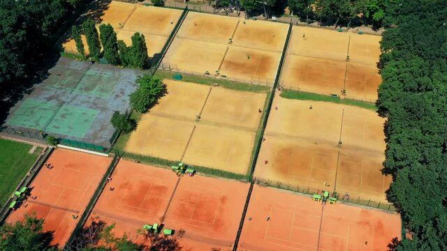 Moisture and watering clay tennis courts - aerial timelapse: athletes and staff of tennis courts move quickly: timelapse. Training on the courts, Moisturize clay tennis courts.