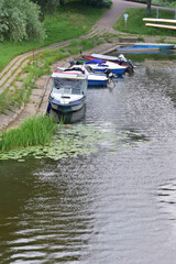 Motor boats moored to the shore in the marina. Day. Summer.