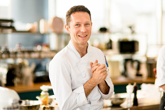 portrait of smiling male chef in on blurred kitchen background