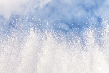 Background of water jets and fountain splashes against a blue sky with clouds