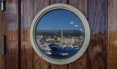 the picturesque harbor is reflected through the porthole of the ship, Split, Croatia