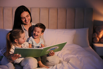 Mother reading bedtime story to her children at home
