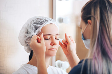 Cosmetolog beauty master making marks with a thread before the permanent makeup procedure