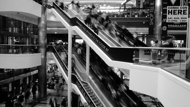 viele personen fahren in einem kaufhaus eine rolltreppe herunter 