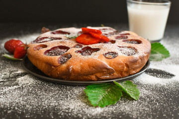 Homemade pie with strawberries, a glass of milk and mint on a dark background.
Home cooking, baking. Handmade dessert