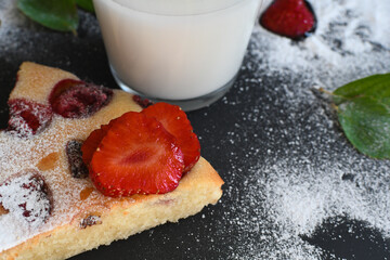 Homemade pie with strawberries, a glass of milk and mint on a dark background.
Home cooking, baking. Handmade dessert