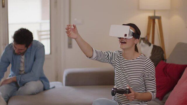 Young woman playing virtual reality game with console on couch