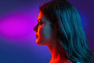 Caucasian young woman's portrait on dark studio background in neon. Concept of human emotions,...
