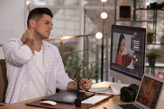 Tired retoucher at table with modern computer in office