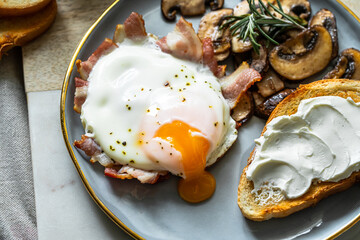 Breakfast with fried egg(sunny side up) with bacon, grilled with rosemary mushrooms and toast with cream cheese