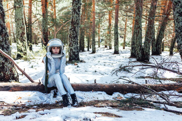 Determined female in space helmet sitting in snowy forest