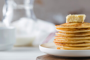 The pancakes are stacked in a plate with a piece of butter and drizzled with honey sauce. Breakfast concept.