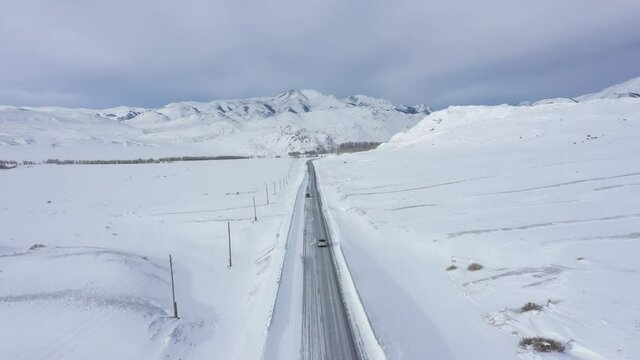 Aerial view of cars driving winter road. Scenic landscape covered by snow. Altai republic nature. Chuiskiy trakt road