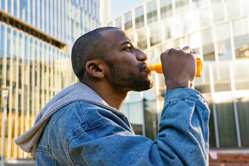 Black man drinking delicious beverage on city street