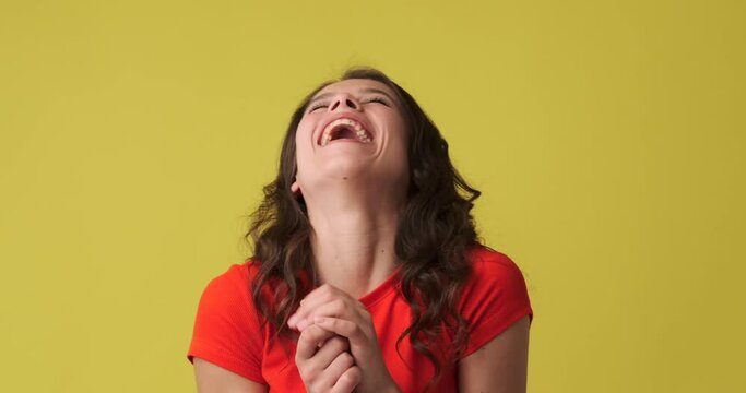 Beautiful woman laughing out loud over yellow background