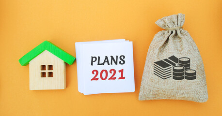 A note with the words plans 2021, a house and a money bag. Real estate concept. Family budget...