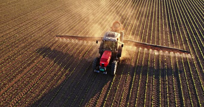 Tractor spraying fertilizer on soybean field