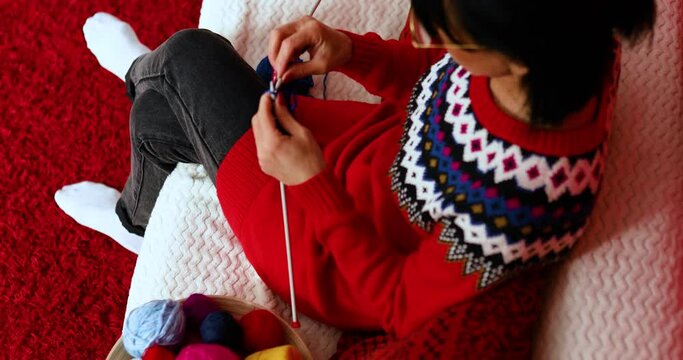 Mature female sitting in comfortable sofa and knitting while enjoying weekend at home, Senior woman knitting, relax at home do favorite hobby activity on weekend, wellbeing concept