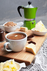 KETOGENIC KETO DIET DRINK. Coffee and cocoa mixed with ghee. Cup of bulletproof coffee with cocoa and ingredients on wooden background