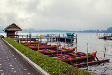 Fototapeta na wymiar raditional Balinese perahu red boats (fishing boats) on Lake Beratan near Pura Ulun Danu temple and Bedugul mountains