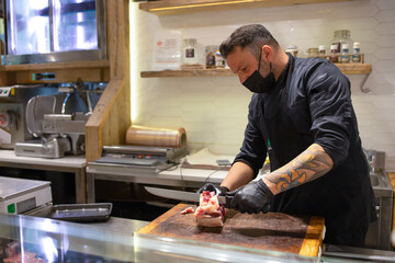 Butcher cuts up a piece of fresh farm meat in his store