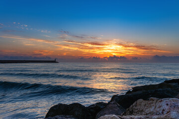 Fototapeta na wymiar Sunrise from the port of Gandia, with beautiful clouds on the horizon.