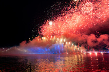 Festive colorful fireworks and illumination in dark sky with beautiful reflection in water. Holiday SCARLET SAILS. High quality photo