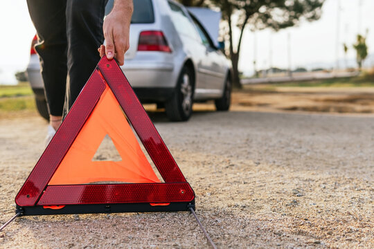 Driver putting red triangle near broken car