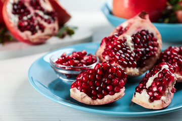 Delicious ripe pomegranates on white wooden table, closeup