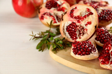 Delicious ripe pomegranates on white wooden table, closeup. Space for text
