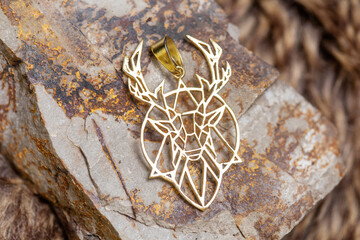 Brass metal pendant on natural background in the shape of Deer animal