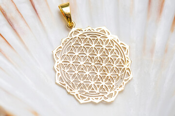 Brass metal pendant on natural background in the shape of flower of life sacred geometry