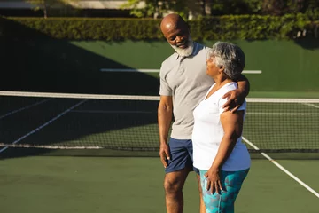 Foto op Canvas Portrait of smiling senior african american couple embracing on tennis court © wavebreak3