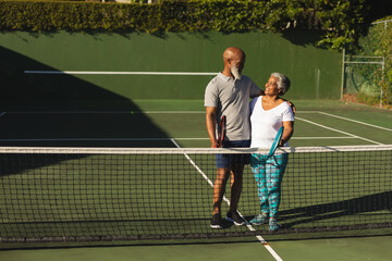 Obraz premium Portrait of smiling senior african american couple with tennis rackets on tennis court