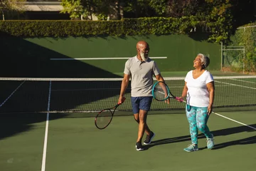 Rolgordijnen Portrait of smiling senior african american couple with tennis rackets on tennis court © WavebreakMediaMicro
