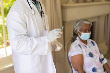Fototapeta premium Senior african american woman in face mask receiving vaccination