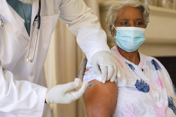 Senior african american woman in face mask receiving vaccination